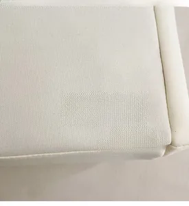 Close-up of a cream canvas tote bag featuring a brown leather patch with debossed text
