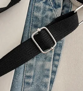 Adjustable black woven shoulder strap with polished silver metal buckle on a fabric bag