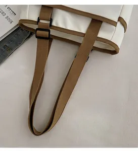 Detail showing the adjustable brown woven handle with black buckle on a canvas tote bag