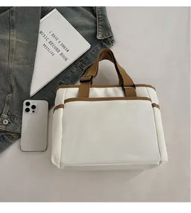 Detailed shot of white canvas tote bag with brown straps alongside everyday essentials