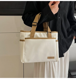 Detail of off-white canvas tote bag featuring brown adjustable strap and brand tag