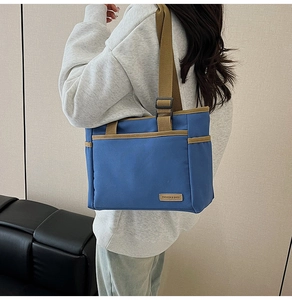 Detailaufnahme der blauen Canvas-Tasche mit Vordertasche und modischem Logo-Aufnäher