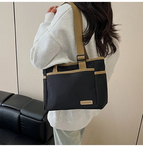 Detail of black canvas tote bag showing khaki straps and fashion logo leather patch