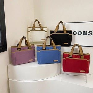Cinq sacs fourre-tout en toile colorés en violet, bleu, rouge, crème et noir sur un présentoir
