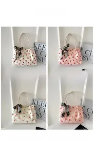 Detail showing various corduroy tote bags with strawberry and cherry patterns and scarves
