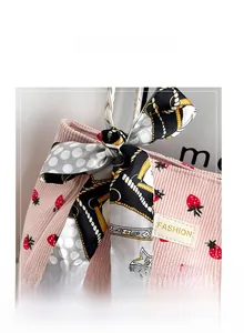 Detail of pink corduroy tote bag with strawberry print and decorative silk scarf