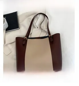 Detail view of burgundy and beige tote bag with gold metal buckle on adjustable strap