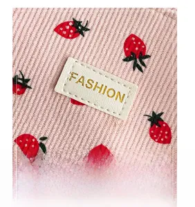 Close-up of pink corduroy fabric with strawberry print and gold FASHION label