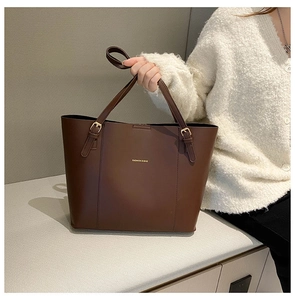 Close-up of dark brown PU tote bag featuring gold hardware and adjustable shoulder strap
