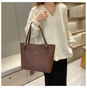 Detail of dark brown tote bag showing the gold fashion logo and textured PU leather finish