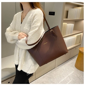 Detail of dark brown leather tote bag with FASHION & BAG text and adjustable strap