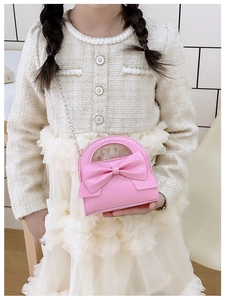 Close-up of pink girls' bow crossbody bag with fine metal chain strap and leather texture