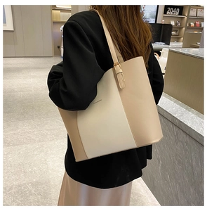 Detail of adjustable metal buckle on beige leather tote bag shown in bookstore setting