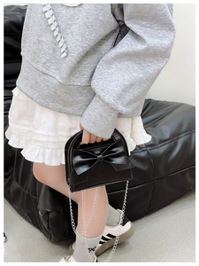 Detail of a mini black bow handbag for girls featuring a stylish silver metal chain strap