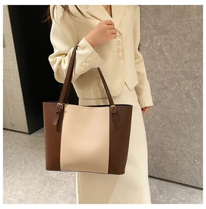 Detail of adjustable metal buckle and leather strap on a two-tone minimalist tote bag