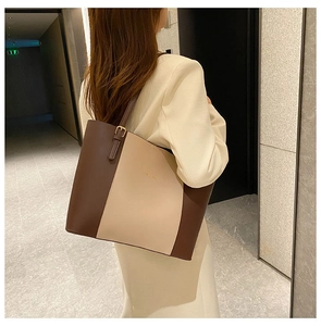Side view of a large two-tone brown and beige tote bag with adjustable shoulder strap