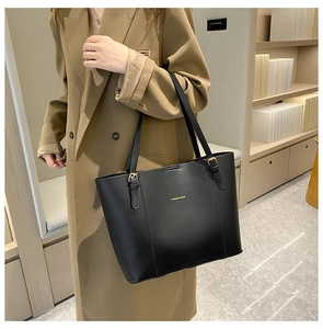 Detail of black leather tote bag with gold lettering and adjustable metal buckle