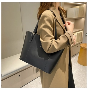 Detail of black leather tote bag with adjustable strap and gold fashion lettering