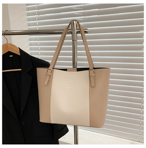 Close-up of color-block tote bag with gold logo and adjustable shoulder strap