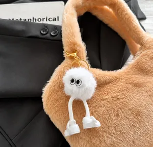 Détail d'une breloque en peluche blanche avec des yeux sur un sac à main en fourrure orange