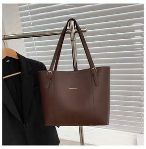 Detail of coffee brown leather tote bag with gold hardware and logo on a display stand
