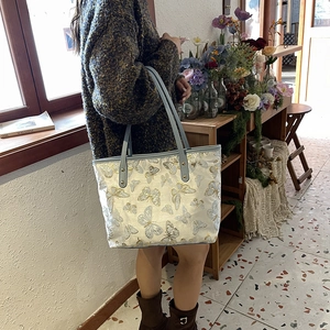 White butterfly embroidery tote bag with grey leather straps shown on a female model