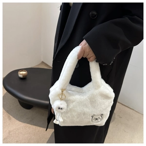 Détail d'un sac cabas en fausse fourrure blanche avec broderie ours et breloque peluche