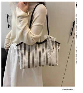 Detalle del bolso tote de lona a rayas con lazo de encaje blanco y asas marrones