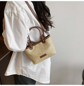 Détail du sac seau en paille tissée avec garniture en similicuir marron et poignée nouée
