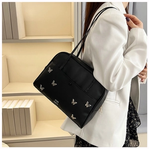 Détail du sac bandoulière noir avec breloque papillon argentée et lettrage de marque