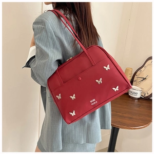 Détail du sac fourre-tout rouge avec papillons métalliques et texte imprimé élégant