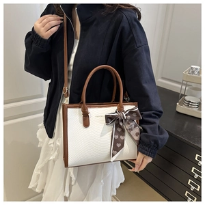 Détail d'un sac cabas blanc motif crocodile avec anses brunes et foulard décoratif en soie