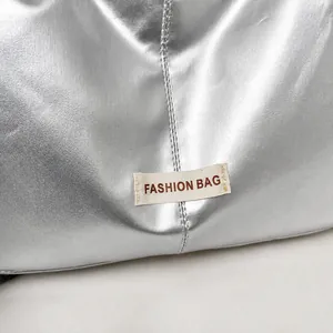 Detail van zilveren metallic textuur met Fashion Bag stoffen label en stiksels