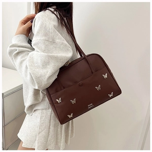 Détail du sac cabas marron foncé avec papillons métalliques porté à l'épaule