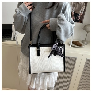 Dettaglio della borsa tote a contrasto con pelle coccodrillo e foulard sul manico
