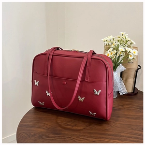 Détail du sac cabas bordeaux avec breloques papillon en argent sur table en bois
