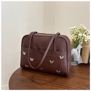 Détail d'un sac cabas marron vintage avec boucles papillon argentées sur bois