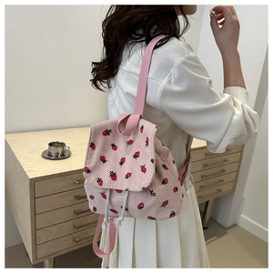 Detail view of pink corduroy mini backpack with strawberry embroidery and drawstring closure