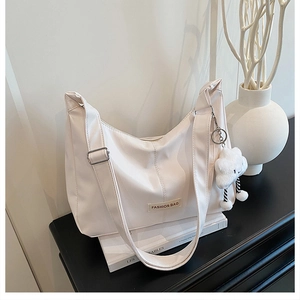 Detailweergave van de witte Hobo-schoudertas met pluchen wolkbedel op een standaard