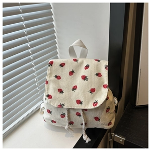 Detailed view of cream corduroy mini backpack with red strawberry print and drawstring lid