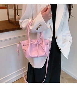Detalle del bolso de charol rosa con decoración de lazo y herrajes dorados elegantes