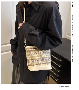 Detail of woven straw shoulder bag with metallic finish and white leather trim