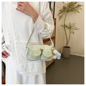 Détail du sac bandoulière à carreaux vert clair avec breloques en peluche et petites poches