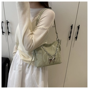 Détail du sac en cuir verni plissé vert clair avec chaîne argentée et bijou papillon