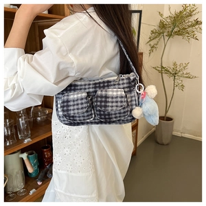 Détail du sac à bandoulière à carreaux avec poches avant et pendentif en peluche bleu