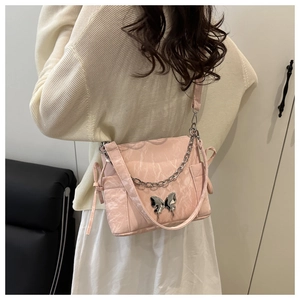 Détail du sac à bandoulière matelassé rose avec breloque papillon et chaîne argent