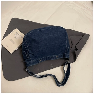 Detailed close-up of dark denim tote bag featuring white stitching and metal rivets