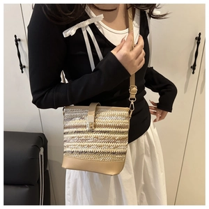 Detailed close-up of woven patchwork bucket bag with metallic texture and leather trim