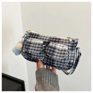 Détail du sac à bandoulière à carreaux gris avec double poches et pompon bleu doux