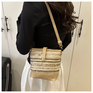 Detail of woven straw bucket bag showing leather base and adjustable crossbody strap
